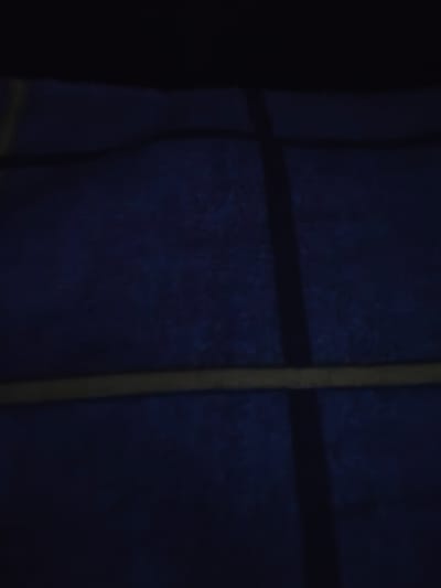The image shows a dark, textured blue surface with horizontal and vertical lines. It appears to be a floor or wall with a grid pattern. The lines are lighter in color, possibly yellow or beige, and create distinct rectangular sections within the dark blue surface. The lighting is dim, creating shadows that obscure some details of the pattern and texture. The overall impression is of an indoor or outdoor space with a structured, possibly utilitarian, design. No people or specific objects are discernible in the image, nor is there any indication of the city of Ishim, Russia, within the visual content.