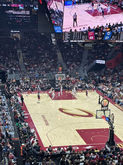 The image depicts an NBA basketball game at Rocket Mortgage FieldHouse in Cleveland, Ohio. The Cleveland Cavaliers are playing against the Washington Wizards. The game is in the second quarter with 7:57 remaining. The Cavaliers are leading 49 to 27. Players are on the court and a large crowd is in attendance. Visible advertisements include Lexus, TrustedSec, Redfin, Cleveland Clinic, and SeatGeek. The scoreboard shows player statistics for both teams. A 50/50 raffle with a prize of $12,592 is in progress.