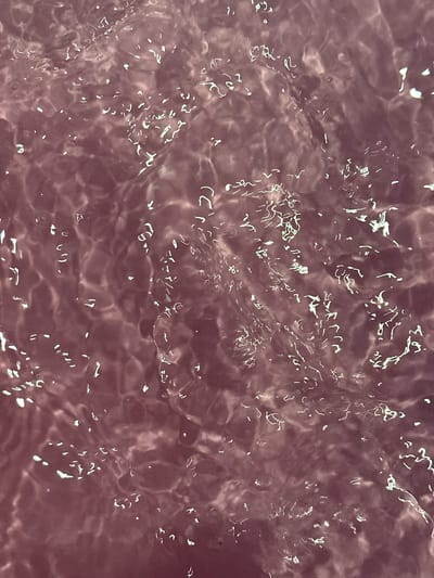 This is a close-up, overhead shot of disturbed, reddish-brown water, possibly from a bath or tub, showing reflections and ripples on the surface. There are no people, buildings, or any discernible elements of the city of Mozhga, Russia, present in the image.