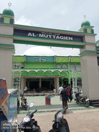 The image shows the entrance to Masjid Jami' Al-Muttaqien Jagapura. The building features a white dome and green accents. People are entering the mosque. Several motorcycles are parked in front. A sign on the left displays "Al-Jawal". The image is stamped with "vivo Y19s" and a date "6 Feb 2026, 12:05" along with the names "Akhtar & Arvan".