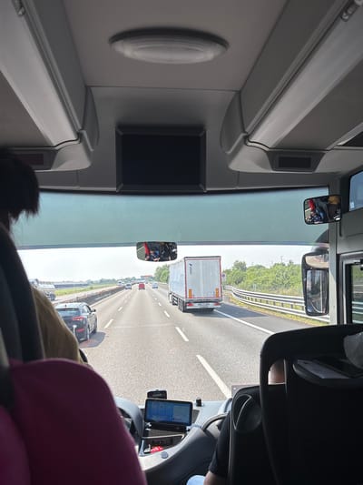 The image shows the view from inside a vehicle, likely a truck or bus, traveling on a highway. The perspective is from the driver's seat, looking forward through the windshield. Traffic is visible on the highway, including trucks and cars. Guardrails and greenery border the roadway.
Parma, Italy is not definitively determined as the location based on the image alone. Further information is required to confirm the location in Parma, Italy.