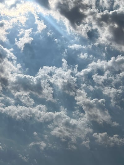 The image shows a cloudy sky with visible sunbeams breaking through. The clouds are varied in density, with some appearing white and puffy, while others are darker and more ominous. The overall impression is one of a dramatic and dynamic sky, possibly before or during a storm. There is no indication of the city of Ringsted, Denmark, or any specific geographical location within it. The image is a close-up view of the sky and does not contain any people, subjects, objects, or actions.