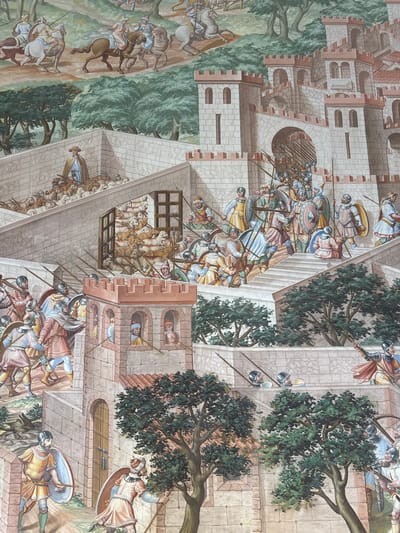 This fresco depicts a bustling scene of military activity and civilian life within and around a fortified city, likely San Lorenzo de El Escorial, Spain, given its characteristic architectural style. The fresco showcases multiple levels and elements.

In the upper portion, horsemen in historical attire are depicted moving across a landscape with trees. Below them, the city walls and towers are prominent. A large gatehouse with an arched entrance is a focal point, with many soldiers armed with spears and shields gathered both inside and outside the gateway. Some figures are seen climbing stairs towards the upper ramparts, indicating movement and defensive preparations.

On the left side of the fresco, a shepherd with a staff guides a flock of sheep up a stone staircase towards a fortified area. Further down on the left, a soldier in a yellow tunic and a blue shield stands guard.

Throughout the scene, numerous individuals are depicted in various states of action. Soldiers are shown in formation, some with helmets and armor, others with spears and shields. Civilians, including the shepherd and people interacting near the gate, are also visible. The architecture is detailed, featuring stone blocks, battlements, and arched openings. Trees with dense green foliage are interspersed throughout the scene, providing a natural contrast to the man-made structures. The overall impression is one of a dynamic and well-defended settlement.