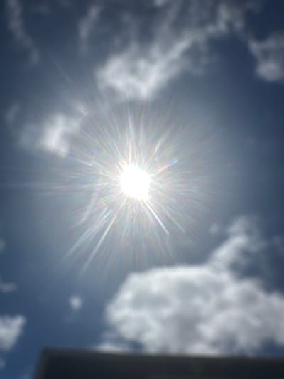 The image is a photograph of the sun shining brightly in a cloudy sky. The sun is in the center of the image, with rays of light extending outwards. There are several clouds in the sky, some of which are white and fluffy, while others are darker and more ominous. In the foreground, there is a dark, blurry shape that appears to be a building or structure. The overall impression is one of a bright, sunny day with a hint of impending weather.

The image is not specific to Tewkesbury, United Kingdom, as it is a general scene of the sun and sky. There are no identifiable landmarks or features that would indicate a specific location.