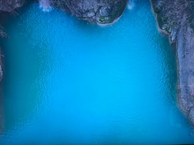 The image depicts a body of turquoise water surrounded by rocky cliffs with some vegetation. The water surface is rippled. Bare tree branches are visible along the cliff edges. The location is not discernible from the image alone. Therefore, it is not possible to confirm its location within Basingstoke and Deane, United Kingdom.