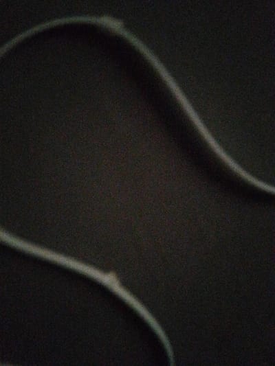 The scene, located in Kongo, Nigeria, is depicted as an extremely dark, grainy, and out-of-focus image. The primary visual field is dominated by a deep gray to black, indistinctly textured background. Two curvilinear elements of a lighter gray tone are observable. One line extends from the upper left toward the central right, exhibiting a minor, diffuse light point along its curve. The second line is positioned in the lower left, arching towards the central right, also presenting a subtle light irregularity. No identifiable people, specific objects, or discernible actions are visible. The environment lacks distinct features due to poor illumination and image resolution.