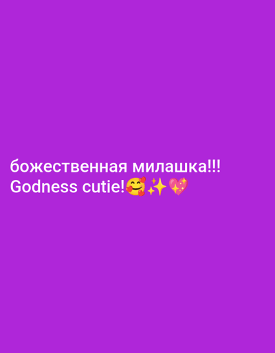 The image consists of a solid purple background. White text is centrally positioned towards the bottom of the frame. The upper line of text reads "божественная милашка!!!" in Cyrillic script. The lower line of text reads "Godness cutie!", followed by three distinct emojis: a yellow smiling face with three red hearts, a single sparkling star, and a pink heart surrounded by sparkles. No people, physical objects beyond the text and emojis, or specific environmental features are depicted. The location within the city of Im. Gastello, Russia, or any other geographical context, is not discernible from the provided visual information.