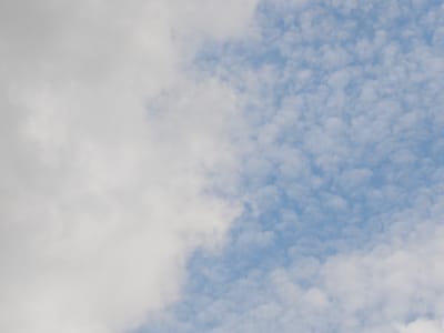 The image shows a cloudy sky with a distinct division between large, white, fluffy clouds on the left and a patch of scattered, smaller, puffy clouds against a bright blue sky on the right. There is no indication of the city of Koledino, Russia, or any other terrestrial features or human presence.