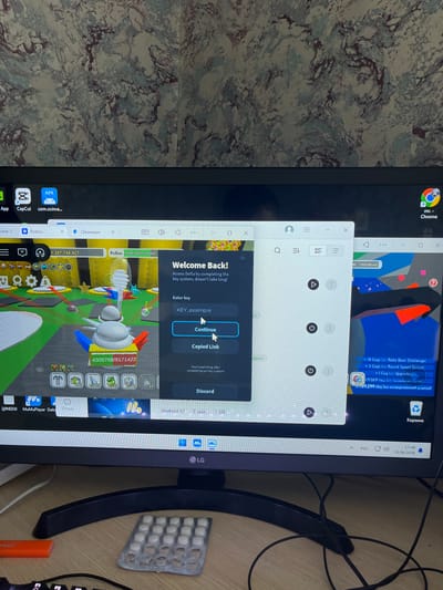 This is a vertical, eye-level, close-up shot of a computer monitor display, with a portion of a desk and a blister pack of pills visible on the right. The monitor displays a desktop environment with several open windows. The dominant activity appears to be gaming, as indicated by the game interface visible in the lower half of the screen, which shows in-game currency ("Pollen," "Cogs," "Med") and resource counters.
At the top of the monitor, the Google Chrome browser is open, showing a tab with a game-related webpage featuring text like "+18 Cogs (от Robo Bear Challenge)" and "+9.069 Мед (от Тыквенная патча)". Another window is a pop-up with the title "Welcome Back!" and fields for "Enter key" and "KEY_example," along with "Continue" and "Copied Link" buttons, suggesting a key input or redemption process for the game. There's also a Discord application window visible.
The operating system taskbar is partially visible at the bottom, showing icons for "APK," "CapCut," and "Roblox," along with system information like "Android 12," "3 ядро 4 GB," and the date "29.06.2026." The time "17:46" is also displayed.
The background of the desktop appears to be a textured wallpaper. A blister pack with approximately 25 white pills is positioned on the desk to the right of the monitor, and part of a black keyboard is visible. The overall impression is of a person using a computer for gaming and potentially interacting with online communities or services related to the game. The lighting suggests an indoor setting, likely during the day or evening.