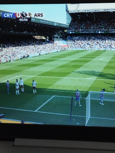The image shows a soccer game between Crystal Palace (CRY) and Arsenal (ARS). The score is 0-1 in favor of Arsenal, and the game clock reads 46:46. The game is taking place in a stadium with a large crowd. Players in the foreground stand on the field. The image does not provide information to confirm the game is in Bitterfeld-Wolfen, Germany.