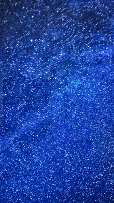 This is a close-up, abstract image of a dark blue background heavily speckled with numerous small white dots. The dots vary in size and intensity, giving the impression of a starry sky or a textured, illuminated surface. There are no discernible people, objects, actions, or interactions. The environment is not identifiable, and it is not possible to determine if the image is related to Володарский ауылдық округі, Kazakhstan.