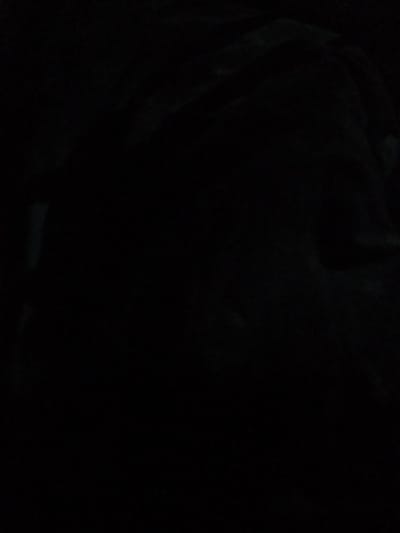 The image is extremely dark, making it difficult to discern any specific details. The overall impression is one of near-total blackness, with some faint, indistinct shapes that could be interpreted as fabric or a very dark surface. There are no discernible people, objects, actions, interactions, or environmental features visible that would allow for identification of a location within Kara-Bak, Kyrgyzstan, or any other specific place.