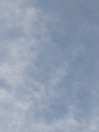 The image is an outdoor, close-up shot of a cloudy sky with a subtle grain texture. The color palette consists primarily of muted blues and whites, indicative of daytime. There are no discernible structures, people, or objects visible within the frame, suggesting that the photograph solely captures the atmospheric conditions. The absence of any specific landmarks makes it impossible to pinpoint a location within the city of Vulcănești, Moldova, or any other geographical area. The image focuses on the abstract patterns and textures of the clouds against the sky.