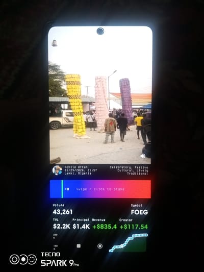 The image displays a smartphone screen capturing a cultural event with decorated pillars. The scene, identified as Lekki, Nigeria on January 24, 2026, at 21:57, is tagged as "Celebratory, Festive, Cultural, Lively, Traditional." The screen shows a staking option, volume of 43,261, the symbol "FOEG," and values for TUL ($2.2K), Principal Revenue ($1.4K), and Creator (+$117.54). The phone is a TECNO SPARK 9 Pro.