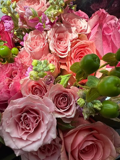 This is a close-up image of a bouquet of flowers, mainly roses, with varying shades of pink. There are also some green berries interspersed among the roses.
The location is the city of Sunrise, United States of America.