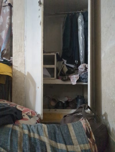 The image shows the interior of a cluttered closet or storage space. The main subjects are various articles of clothing and other items piled haphazardly on shelves and within compartments. There are no people visible. The setting appears to be a domestic storage area, possibly in Abbottabad, Pakistan, given the context.
The items include what looks like folded clothes, some in plastic packaging, and several bags or pouches. One shelf has a white compartment with some papers visible inside. A darker-colored bag or backpack is also present, along with what appears to be a patterned blanket or fabric draped over some of the contents. The overall impression is one of disarray and a lack of organization.
There are no obvious clues about the time of day or weather, but the lighting suggests it is indoors. The location cues are limited to the generic nature of a storage closet. No text is clearly legible in the image. The activity taking place is simply the storage of personal belongings. The scene evokes a sense of everyday domestic clutter.