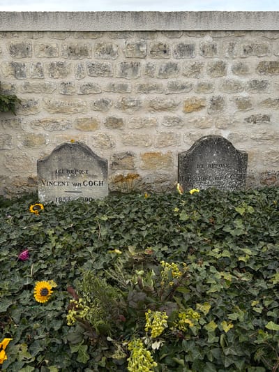 The image shows the graves of Vincent and Theo van Gogh at the Auvers-sur-Oise cemetery in France. The stone wall and ivy-covered ground are visible. Two stone grave markers are present. One is inscribed "ICI REPOSE VINCENT VAN GOGH 1853-1890" and the other "ICI REPOSE THEODORE VAN GOGH". Several sunflowers are visible near the graves.