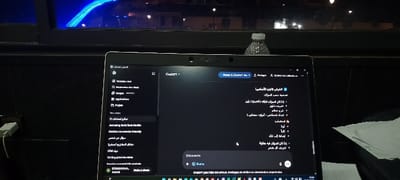 A laptop screen displays the ChatGPT interface in a dark mode theme. The left sidebar contains options like "New chat," "Images," "Applications," and "Projects." The main content area shows a conversation or document with text in Arabic. Some topics include a review of essential topics, definitions, and characteristics. There is also a search or input field with options for both text and voice input. The time displayed on the screen is 20:50. A water bottle is at the top of the screen.