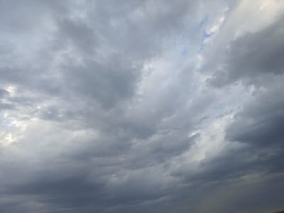 This media file captures a dramatic sky filled with dense, grey clouds, suggesting overcast or stormy weather. The clouds are varied in texture and density, with some appearing lighter and more diffused, allowing glimpses of a pale blue sky in a few small areas. The overall impression is one of an impending or ongoing weather event. The light is subdued, indicating it is likely late afternoon or early evening, or that the sun is heavily obscured by the cloud cover. There are no discernible objects, people, or specific location cues within the frame; the focus is entirely on the atmospheric conditions. The image evokes a sense of vastness and the power of nature.