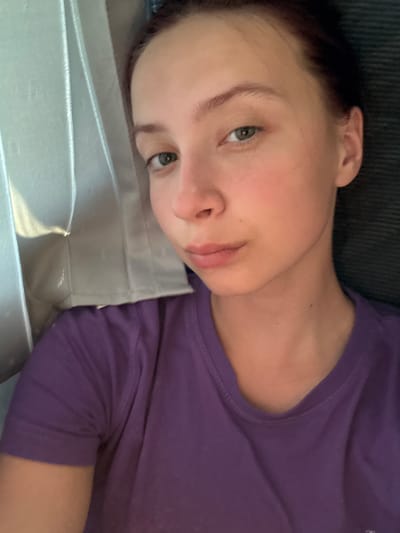 A young woman is lying down, her head resting on a pale, possibly satin, surface. She is wearing a purple shirt. The background appears to be a dark corduroy surface. The location, Staryi Chul'tem, Russia, is not visually confirmed in the image.