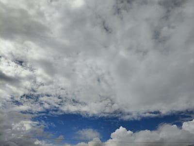 The image shows a cloudy sky with patches of blue visible. The clouds are varied in texture and density, with some appearing fluffy and white, while others are darker and more uniform, suggesting different altitudes or atmospheric conditions. There is a thin black horizontal line across the bottom of the frame, which appears to be a power line. The scene depicts an outdoor environment under a dynamic sky. The location in Petrovsk, Russia is inferred from external context and not directly visible in the image.