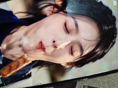 The image shows a close-up, tilted shot of a young woman with her eyes closed, appearing to be asleep or in a relaxed state. She has dark hair, and her face is softly lit. In the foreground, a skewer with a cooked sausage is held close to her mouth, with some white substance, possibly smoke or steam, rising from it.
The woman is wearing a dark blue garment with white and red trim, suggesting a uniform or casual attire. The background is softly blurred, with hints of green and beige, not providing specific location cues.
The scene appears intimate and candid, possibly capturing a moment of rest or enjoyment. There is no discernible time of day or weather information.
Visible text in the image includes "0.10" in the upper right corner, which could be a timestamp or part of a screen display. The overall mood conveyed is one of peacefulness. The location context provided is Palangka Raya, Indonesia.