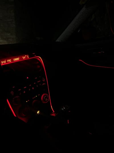 The image shows the illuminated center console of a car interior at night. The console has red accent lighting. The display panel shows "3:40 FM2 10000 5". Buttons for CD, TAPE/MD, AM, FM1, and FM2 are visible. Other features include volume, power, auto, a/c, and dimmer. The scene is very dark and only details illuminated are visible. There is no information about the location in the city of Kribul, Bulgaria, or any people, subjects, objects, actions, or interactions that can be extracted from the given image.
