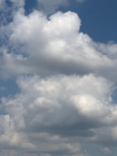 The image is a close-up, vertical shot of a cloudy sky with patches of blue. The clouds are varied in texture and density, with some appearing bright white and fluffy, while others are darker gray and more diffused. The lighting suggests it is daytime, possibly late morning or early afternoon. There are no people, subjects, or objects visible in the frame other than the clouds and sky. The image does not provide any specific visual cues to indicate a location within the city of Bol'shie Kabany, Russia.