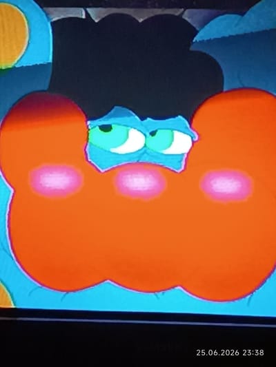 The image shows a close-up of a cartoonish, stylized face with large, orange cheeks that resemble large, puffy lips. The face has big, green eyes with white pupils, giving it a somewhat sleepy or bored expression. There are two pink, circular blush marks on each of the orange cheeks. The background is a mix of dark blue and black shapes, possibly representing hair or a stylized environment. The overall style is simple and bold, with bright, flat colors. In the bottom right corner of the image, there is a timestamp that reads "25.06.2026 23:38". The location context provided is Bolhrad, Ukraine. The time of day indicated by the timestamp is late evening.