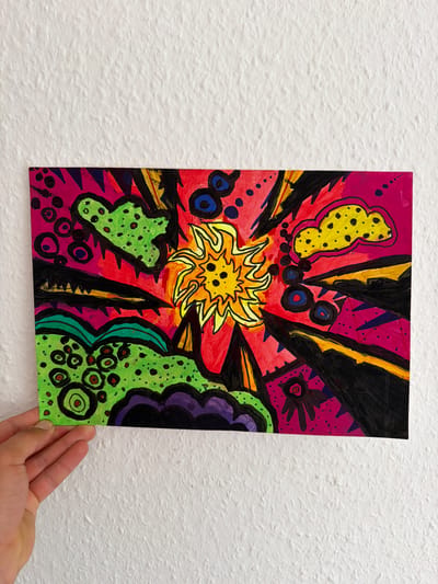 The media file shows a colorful, abstract drawing on paper, held by a person's hand against a textured white wall. The drawing is vertically oriented and features a vibrant explosion of shapes and colors. A bright yellow, star-like sunburst emanates from the center, surrounded by sharp, black and yellow jagged lines against a pink and red background. Various organic shapes, including a yellow blob with black spots, green masses with black speckles, and purple forms, are scattered across the composition, outlined in black. Small circles and dots in blue, black, and red are also present. The overall style is energetic and somewhat psychedelic. The scene appears to be an indoor setting, with the drawing displayed on a wall. There is no visible text in the image. The context of Nienburg/Weser, Germany, is external information not directly derivable from the image content itself.
