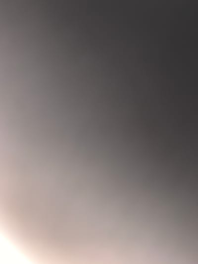 This is a photograph with a gradient of light and dark tones, suggesting a subtle transition from shadow to illumination. The left side of the image is a deep, dark grey, gradually lightening as it moves towards the right. The right side of the image is a bright, soft white, with a warm, almost peachy hue. There are no discernible subjects, objects, or specific scene elements. The lighting suggests that the photograph may have been taken in low-light conditions, perhaps during dawn or dusk, or with a light source directed towards the right side of the frame. There is no visible text. The abstract nature of the image makes it difficult to determine a specific activity, event, or location cues.