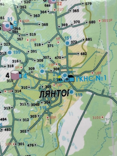 This is a detailed, close-up aerial map of a section of Solnechnyi, Russia, specifically focusing on a forest and an industrial or infrastructure area. The map shows numerous numbered locations, roads, and bodies of water. Key features include:

*   **Roads and Paths:** A network of paved and unpaved roads is depicted, indicated by thick black lines. Some roads have markers with numbers like "31", "4", "199", "315", "314", "311", "312", "301", "10R", "304B", "304", "116", "303", "80P", "119", "1B3", "24P", "18R", "305", "306", "73P", "76", "309", "308", "307", "470", "391", "318", "316", "5P", "367", "28P", "5B3", "366", "323", "317", "519", "28P", "371", "518", "368", "26R", "363", "364", "6B3", "32", "21П", "365", "370", "369", "372", "151", "681", "682", "372", "680", "3011P", "3101O", "679", and "86".
*   **Buildings and Structures:** There are depictions of buildings. A prominent blue building complex labeled "ГКНС №1" (GKNS No. 1) is visible, suggesting a gas pumping station or similar facility. Other structures are indicated by smaller shapes, some with circles suggesting points of interest.
*   **Water Features:** Several bodies of water are shown, represented by light blue shapes. These appear to be lakes, ponds, or possibly marshy areas within the forest.
*   **Vegetation:** The majority of the map is colored green, indicating forest or wooded areas. Some areas are depicted with lighter green or white, suggesting clearings, fields, or possibly water.
*   **Labels:** Various labels are present, including "Лянтор" (Lyantor), likely the name of a settlement or area, and what appear to be river or stream names like "Пекъявин" (Pekyavin) and "Румьян" (Rumyan). There is also a label "Ац-Не" (Ats-Ne).

The map is detailed and appears to be a navigational aid for a specific geographic area, focusing on infrastructure and natural landmarks within a forest setting.