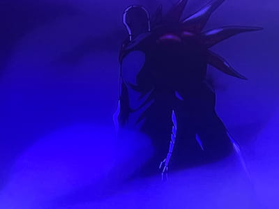 The image displays a stylized, dark silhouette of a figure with a spiky headdress against a vibrant blue, smoky background. The figure is facing away from the viewer, with its head slightly tilted down. The silhouette is predominantly black, with some faint purple or red highlights on the headdress. The blue background appears to be a form of atmospheric effect, perhaps fog or smoke, with varying intensity of blue light creating a dramatic and somewhat mysterious atmosphere. There are no discernible cityscapes or any elements that would indicate a specific location in Shahtinsk, Kazakhstan.