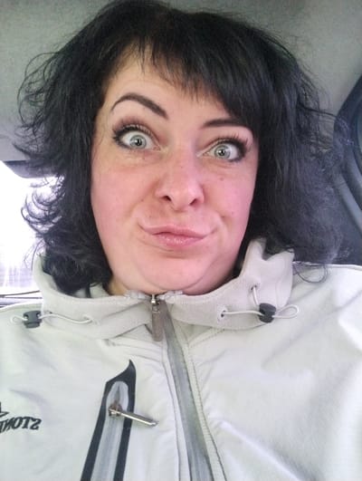 A woman with dark hair and pale skin is taking a selfie. She is wearing a light-colored jacket with a zipper and a hood. Her eyes are wide and her expression is playful. The background appears to be the interior of a vehicle. There is no definitive information to place the subject in Bolgury, Russia.