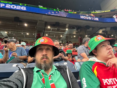 This image captures a vibrant scene at a soccer match, likely in Houston, United States of America, as indicated by the prominent "HOUSTON" text on the large digital display. The people in the foreground are fans, many of whom are wearing green and red, suggesting support for a team, possibly Portugal, given the flag visible. One person wears a green hat with a Portuguese crest, and another has a shirt with "PORT" and what appears to be the Portuguese flag. The atmosphere seems lively and energetic, typical of a sporting event.
In the foreground, a person with a beard wearing a green hat and a red shirt is looking directly at the camera, while another person in the lower left is also facing the camera with a green hat. The background is filled with a crowd of spectators in the stands, also dressed in various colors, and the large electronic scoreboard displaying event information and sponsor logos like "Coca-Cola". The lighting suggests it's likely an evening or indoor event. The digital display at the bottom clearly shows "FIFA WORLD CUP 2026" and "#FIFAWorldCup", indicating the context of the event. The overall impression is one of excitement and shared enthusiasm for the game.