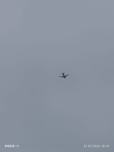 The image shows an airplane in flight against a uniformly overcast sky. The airplane is small and silhouetted against the lighter sky, making it difficult to discern specific details. The sky appears to be a pale gray, indicating cloudy weather. In the bottom left corner of the image, the text "POCO F5" is visible, likely a watermark from the device used to capture the photo. In the bottom right corner, the date "31.07.2026" and time "18:41" are displayed. There are no other discernible objects or subjects in the frame, and no information within the image suggests a connection to Camogli, Italy.