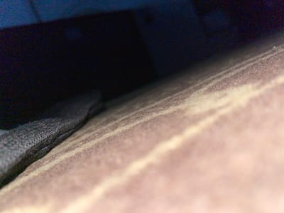 A close-up, low-angle shot depicts a light brown, layered material resting on a black, meshed fabric. Below, the image fades into deep shades of blue and black. The setting or location within the city of Abeokuta, Nigeria is not discernible from the image.