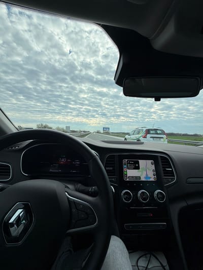 The image is taken from inside a Renault car, showcasing the driver's perspective while driving on a highway. The digital dashboard indicates a speed of 140 km/h. The car navigation system displays a route with the destination being Свиленград, likely located 29 km away. The rearview mirror reflects the sky, suggesting daytime. The image captures the speedometer and the GPS, focusing on the driving experience. There is a car in front that has the license plate PA 8810 MB. The location is Trilistnik, Bulgaria.