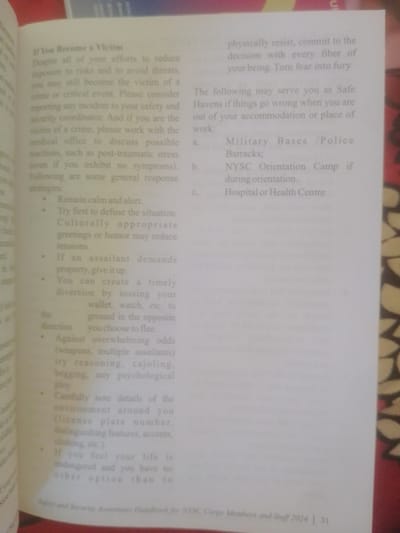 This media file shows a close-up of an open book, likely a handbook, with text visible on both pages. The book's pages are slightly yellowed, suggesting it might be older or printed on a specific type of paper. The primary subject is the text itself, offering guidance and advice.

On the left-hand page, the text is titled "If You Become a Victim" and provides advice on how to respond to crime or critical events, including remaining calm, attempting to defuse the situation, and what to do if property is demanded. It also advises on creating diversions and noting details of the environment. The right-hand page lists "Safe Havens" that may serve as refuges, such as Military Bases/Police Barracks, NYSC Orientation Camps, and Hospitals or Health Centers. The text on the right also mentions physically resisting if necessary and turning fear into fury.

Visible text at the bottom of the image identifies the book as the "Safety and Security Awareness Handbook for NTSC Corps Members and Staff 2024" and indicates the page number as "31".

The setting is indoors, with the book lying flat. The lighting appears to be from overhead, illuminating the text clearly. There are no people or specific objects visible other than the book itself. The image lacks cues for time of day, weather, or specific emotions, as the focus is entirely on the printed content. The location context of Magajin Gari, Nigeria, is not directly inferable from the visual content of the image itself.