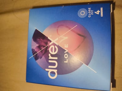 A close-up shot of a blue condom box with the brand name "durex" printed on it in white text. The box is for "durex LOVE" condoms and contains "4 condoms" of the "close fit" variety. The background behind the text includes a circle that has a picture of a couple kissing. The box is positioned on a neutral beige surface. The photo does not contain any information to indicate that it was taken in Elenovo, Bulgaria.