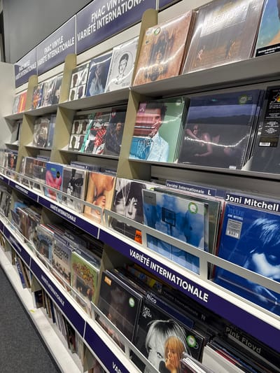 This image shows a selection of vinyl records displayed in a store. The records are categorized under "Variété Internationale," a French phrase that translates to "International Variety." The records are organized on shelves with dividers displaying artist and album titles. Visible artists include Pink Floyd, Joni Mitchell, Nico, Elton John, Foo Fighters, and Kinks. The image also features a label stating "FNAC Vinyle." Given the information within the OCR text, this image was very likely taken at the Fnac store located in Villebon-sur-Yvette, France.