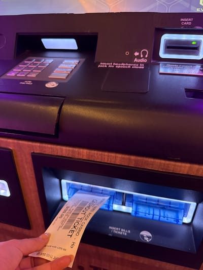 The image shows a close-up of a slot machine at the Seminole Hard Rock Casino in Hollywood, Florida. A hand is pulling a cashout ticket from the machine. The ticket indicates a payout of $120.00. The machine features slots for inserting a card and bills/tickets, as well as an ATM pin pad.