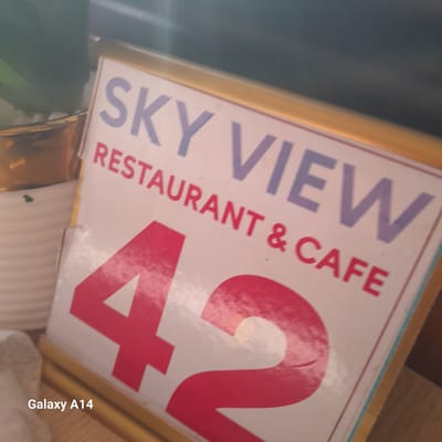 The image shows a sign for "Sky View Restaurant & Cafe 42". The sign is framed in gold and has purple and red lettering. The image includes the "Galaxy A14" watermark in the lower right corner. The location is in Al-Mawasi, Unknown.