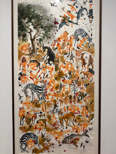 This is a watercolor painting on paper, framed in a thin wooden frame. The artwork depicts a chaotic scene filled with numerous nude and partially clothed human figures, intertwined with various animals. The style is expressive and somewhat surreal, with figures appearing to float or fall through a textured, earthy background.
The subjects include a multitude of human figures, rendered in shades of orange and brown, some with darker skin tones. They are depicted in various poses, suggesting movement, struggle, or perhaps a dreamlike state. Among the animals present are a dolphin, zebras, a large fish, a bull or ox, birds, a deer, and a turtle. Some figures are interacting with the animals, while others seem to be in distress or being carried by them. There are also elements that could be interpreted as abstract shapes or splashes of color, adding to the overall sense of disarray. A prominent tree with dark green foliage is visible on the left side of the composition, rooted in a ground that appears to be made of abstract splotches of color and texture.
The activity or event taking place is not clearly defined, but the composition evokes a sense of an upheaval, a struggle for survival, or perhaps a symbolic representation of human experience. The figures and animals are densely packed, creating a dynamic and visually complex image. There are no clear indications of time of day or weather; the lighting is uniform, and the background offers no environmental cues. The setting is abstract and dreamlike, with no recognizable landmarks or geographical features. The emotions conveyed are a mix of turmoil, desperation, and perhaps a strange sense of abandon.
Notable details include the distinct black and white stripes of the zebras, the smooth, sleek form of the dolphin, and the detailed rendering of the tree. The use of ink splatters and washes creates a textured and organic feel.
There is some visible text in the painting, appearing as handwritten script, primarily on the left side of the artwork and scattered in smaller instances throughout. The text is not easily decipherable from the image.
This artwork is located in La Cuesta, Spain.