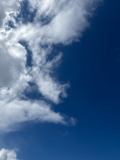 A vertical, close-up shot shows a bright, clear blue sky with scattered, wispy white clouds. The clouds are concentrated on the left side of the frame, with a few smaller ones drifting towards the right. The image captures a sense of open space and natural beauty. This scene could be observed anywhere, including the city of Tamm, Germany.