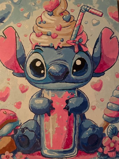 A painting depicts a blue, cartoonish character, resembling Stitch from Disney's Lilo & Stitch, holding a pink, translucent cup filled with a pink beverage. The character has large, dark eyes with white highlights and oversized, pink-lined ears. On top of its head is a swirl of whipped cream adorned with pink hearts and blue berries, topped with a striped straw. The background is a light blue with scattered pink hearts and white shapes. To the left of the character are two pink and blue pastries, and to the right, a stack of pink and blue candies. The painting has a textured, canvas-like appearance. The image is a close-up, detailed view of the artwork, with no elements suggesting a specific urban location like Dubrovka, Russia.