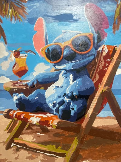 This is a painting of a blue, cartoonish creature wearing orange-rimmed sunglasses, with a pink floppy hat behind it. The creature is looking to the right, with one eye open and the other partially closed. It appears to be lounging or resting on a blue surface. In the foreground, there's a hint of brown foliage on the left and a colorful drink on the right. The background is a bright blue, suggesting an outdoor setting, possibly a beach or tropical location, with some brown wooden structures. The painting has a simplified, stylized aesthetic, with bold brushstrokes and flat areas of color. The overall mood is relaxed and summery. There is no visible text in the image.