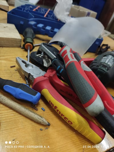 The image shows a collection of tools, including pliers, wire strippers, and a screwdriver, on a wooden surface. The tools are arranged in a cluttered manner, suggesting they are in use or have recently been used. In the background, a blue plastic toolbox is visible, along with a white sheet of paper. The lighting is dim, creating shadows and highlighting the textures of the tools and the wood. The overall scene appears to be a workbench or a similar workspace. The bottom right corner of the image displays the date "22.06.2026" and time "14:36," along with the text "POCO X3 PRO | СОЛОДКОВ А. А." The presence of this text indicates that the photo was taken with a Poco X3 Pro phone, and the name "Солодков А. А." is likely the photographer or owner of the tools. This information, combined with the metadata, could potentially be used to identify the location if the phone's location services were enabled at the time of the photograph and if that data were available. However, based solely on the visual information provided in the image, it is impossible to determine the specific location within the city of Uryupinsk, Russia, or any other city.
