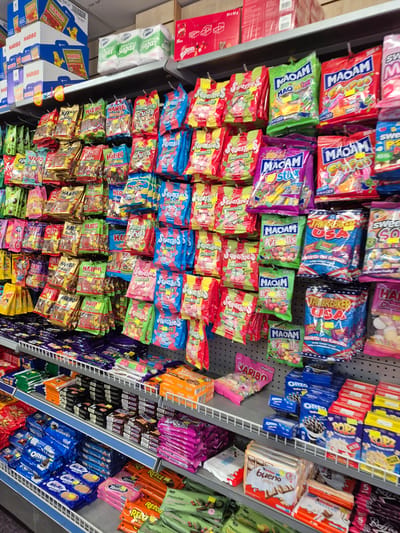 The image displays a shelf-stocking of various confectionery items, including Haribo, Maoam, and other candy brands. These items are arranged in a retail setting, likely a grocery store or convenience store. The arrangement of products suggests a deliberate effort at product placement and display for sale. The store appears to be well-stocked and organized. No people are visible in the image. The lighting suggests an indoor environment, typical of a retail space. The image is taken from a slightly elevated, straight-on perspective, showcasing a substantial quantity of candy. It is highly probable that this image was taken in a shop in Carrick-on-Shannon, Ireland, given the nature of the products and common retail displays found in Irish towns.