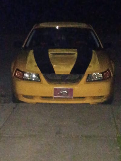 The image shows an aerial view of a yellow sports car parked on a concrete surface. The car is positioned vertically in the frame. It appears to be in a residential or parking area. The lighting suggests it's nighttime. Specific details about people, actions, or interactions are not visible. The location is possibly Clarksville, USA, but without additional information such as street signs, landmarks, or license plate details, it is impossible to confirm.